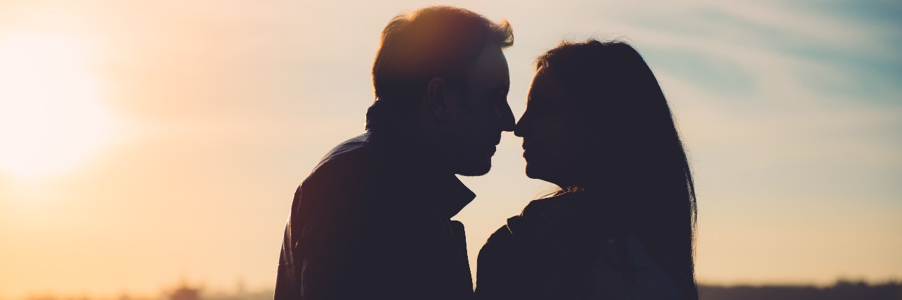 silhouette of man and woman looking into each other's eyes at sunset