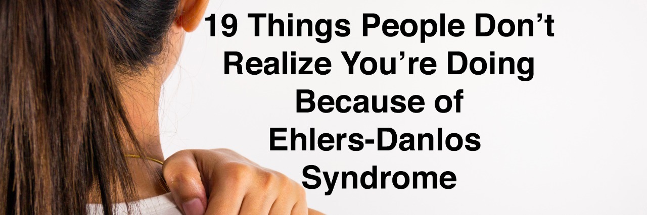 19 Things People Don't Realize You're Doing Because of Ehlers-Danlos Woman holding her painful shoulder with words 19 things people don't realize you're doing because of ehlers-danlos syndrome