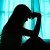 Silhouette of woman sitting in bed by window