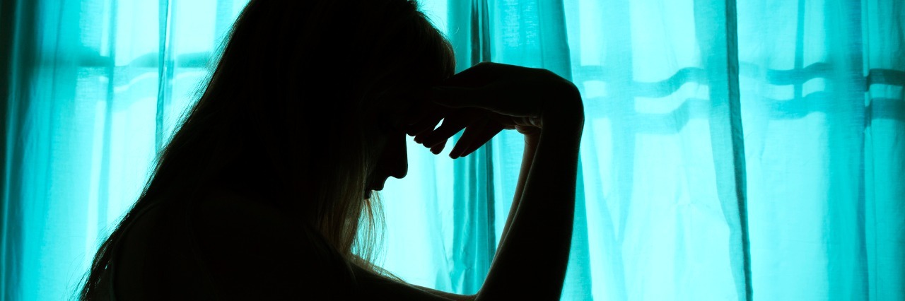 What Chronic Migraine Looks Like Silhouette of woman sitting in bed by window