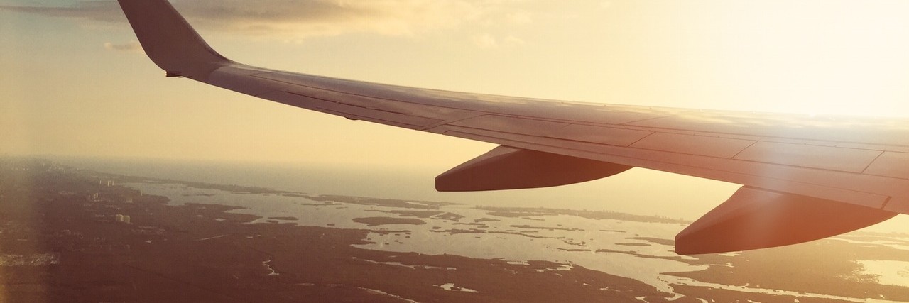 How to Travel With an Anxiety Disorder view of a plane wing from inside a flying plane.