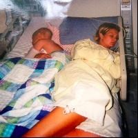 woman and young boy asleep together in hospital bed
