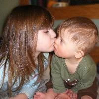 Little girl kissing a baby boy with Down syndrome