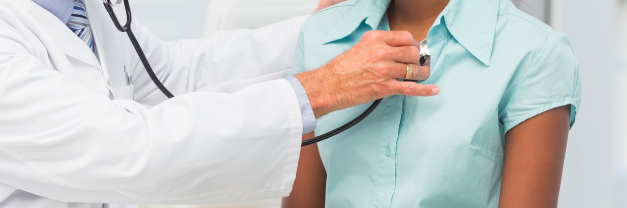 Doctor listening to patients chest with stethoscope in his office at the hospital