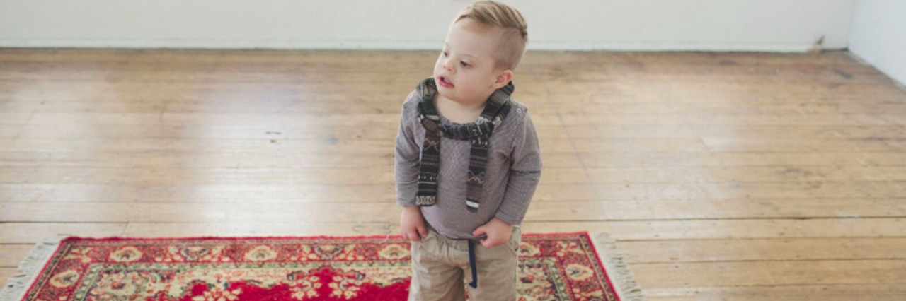 Letter to My Son With Down Syndrome as We Go to Kindergarten Class Boy wearing a backpack, standing on carpet at home