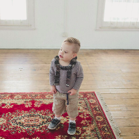 Boy wearing a backpack, standing on carpet at home