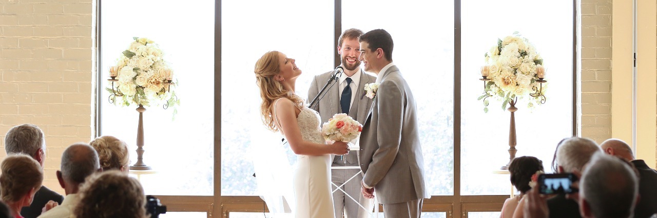 husband and wife standing at the altar getting married and laughing