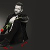 Promo for The Bachelor. Man in a suit holding a rose.
