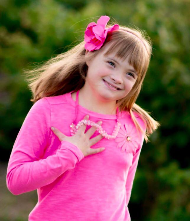 girl with down syndrome wearing pink shirt