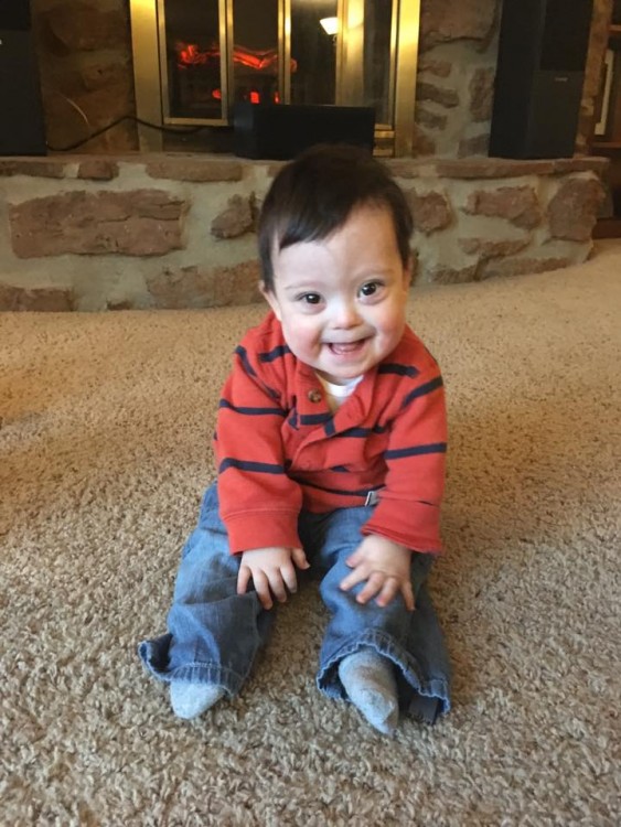 little boy with down syndrome sitting on carpet