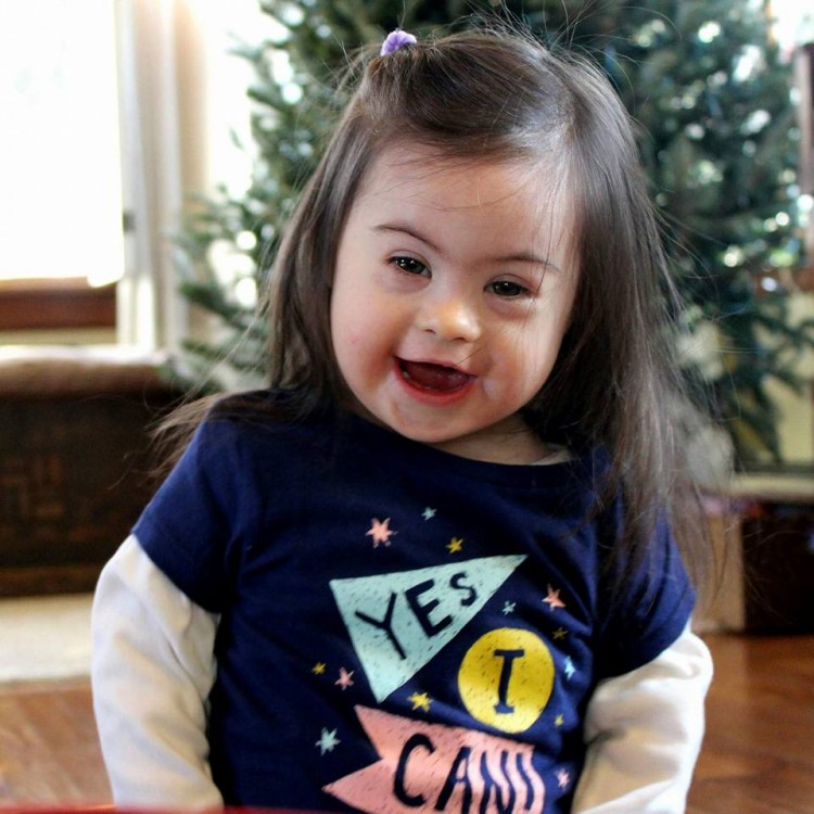 little girl with down syndrome standing in front of christmas tree