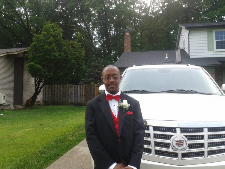 man with down syndrome wearing formal suit standing next to car