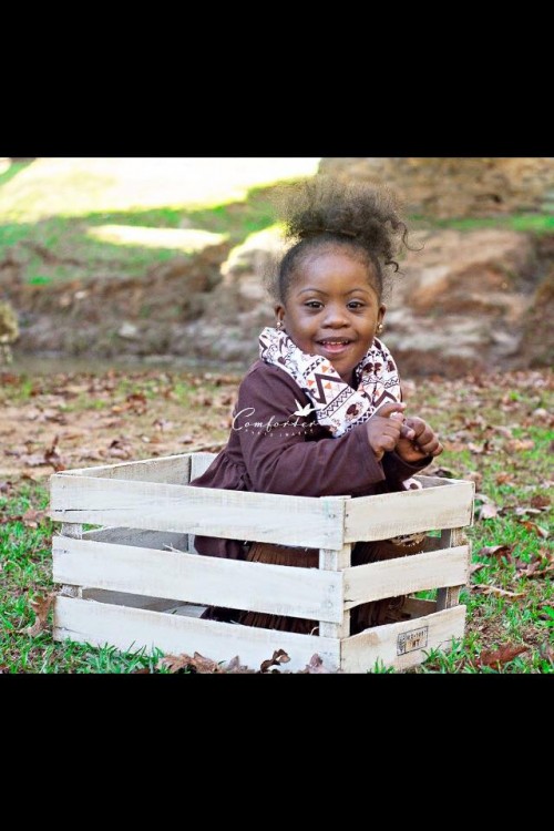 girl with down syndrome sitting outside under tree