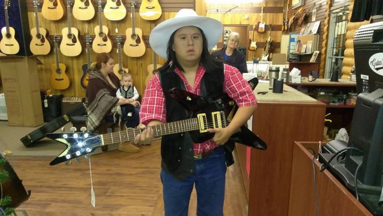 man with down syndrome playing guitar in guitar store