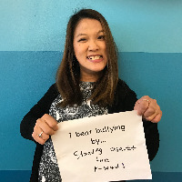 Sarah Kim, a young woman with cerebral palsy, holds up a sign saying 'I beat bullying by standing against the R-word!'