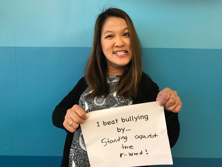 Sarah Kim, a young woman with cerebral palsy, holds up a sign saying 'I beat bullying by standing against the R-word!'