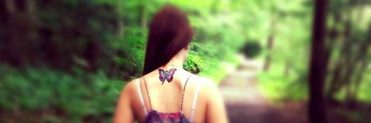 How Rheumatoid Arthritis Taught Me to Be Strong and Fearless A woman hiking, with a butterfly tattoo on her neck.