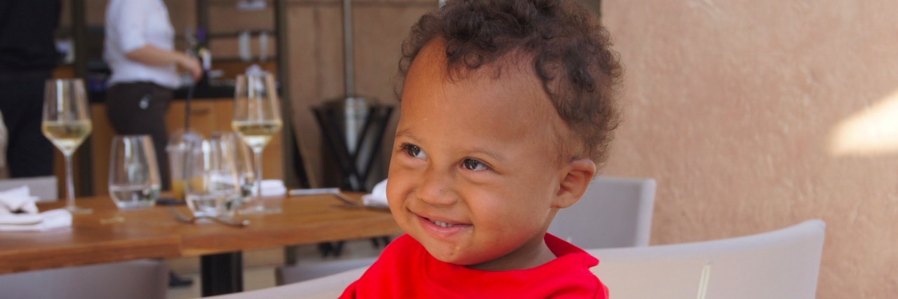 Best Ways to Educate Others About Down Syndrome and Advocate Boy sitting in chair, wearing red shirt and smiling