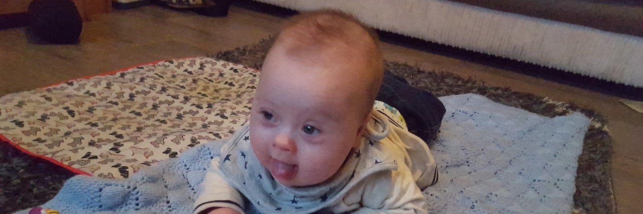 Our Journey After Our Son's Down Syndrome Diagnosis A baby boy with Down syndrome lying on the floor on top of a blue blanket during tummy time
