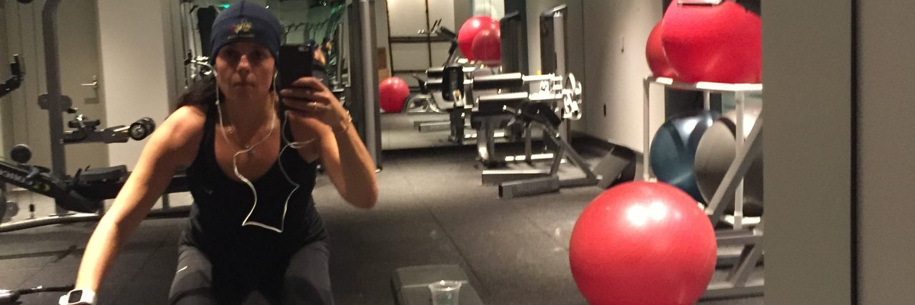 Why I Share Unfiltered Selfies of My Life With Chronic Illness woman doing squats in the gym