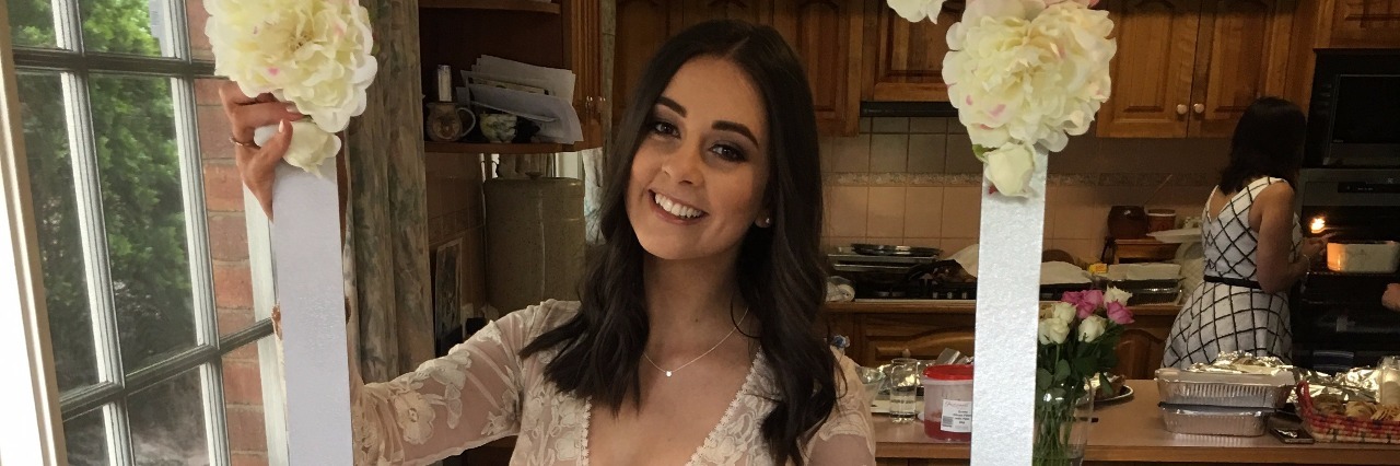 What it's Like to be Diagnosed With a Chronic Illness in Your 20s Young woman holds up a sign for her birthday celebration.