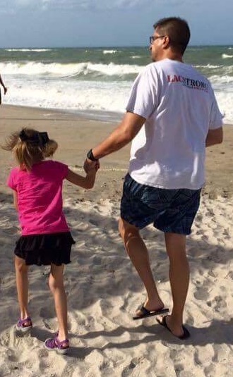 dad holding hands with daughter at beach