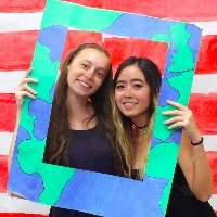 two college girls holding a large frame around their heads