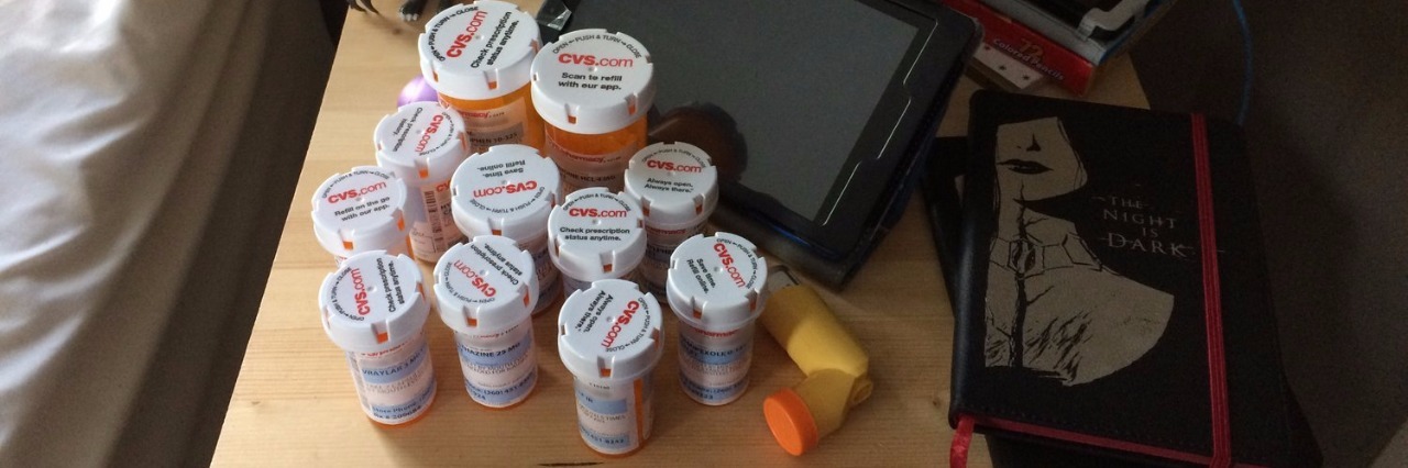 Emma Jones Creates 'The Nightstand Collective' About Chronic Illness Nightstand with multiple pill bottles.