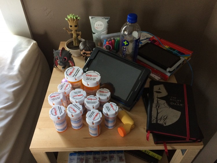 Nightstand with a bunch of pill bottles on it.