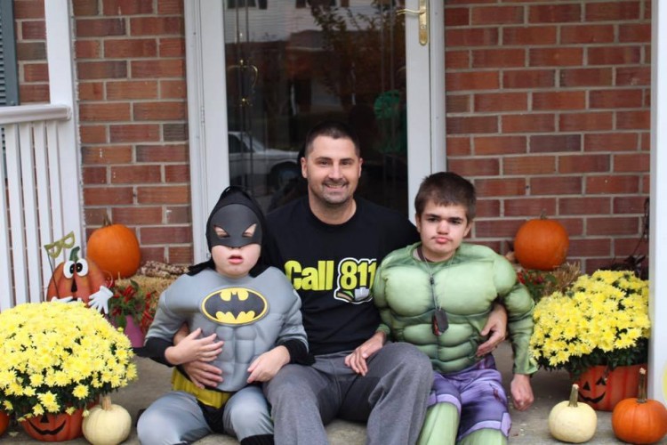 dad sitting on stoop with two kids in halloween costumes