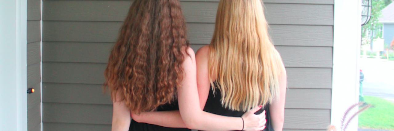 two girls with their arms around each other, back view