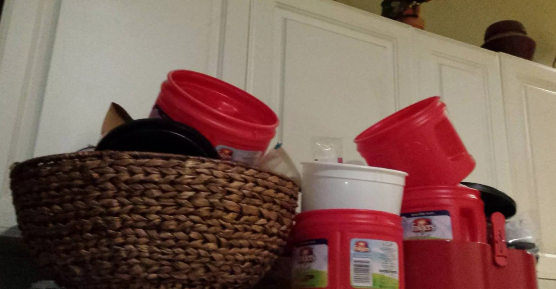 Collection of empty Folgers plastic coffee canisters on top of refrigerator