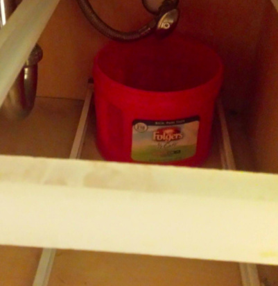 Plastic Folgers coffee can underneath sink
