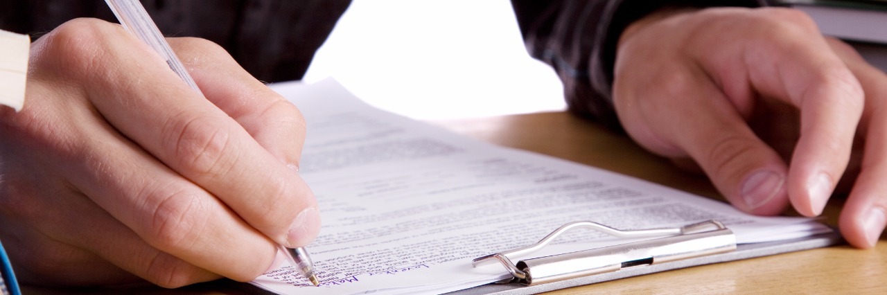 Man sitting and writing something with pen