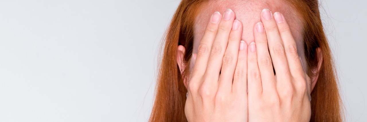 Downfalls of Hiding Primary Immunodeficiency woman with long red hair covers her face with her hands