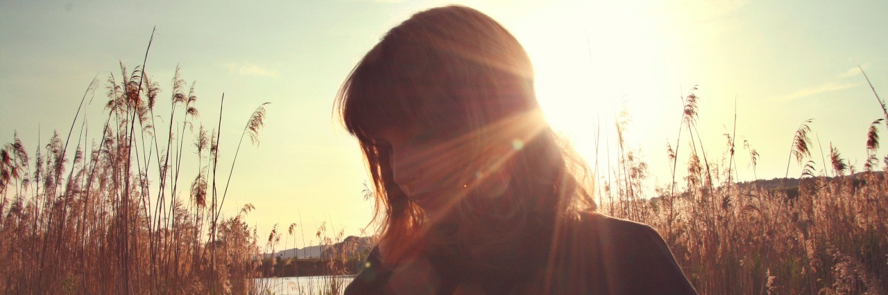 Why I Don't Like Being Called a Victim of My Illness woman in field in silhouette with sun behind her