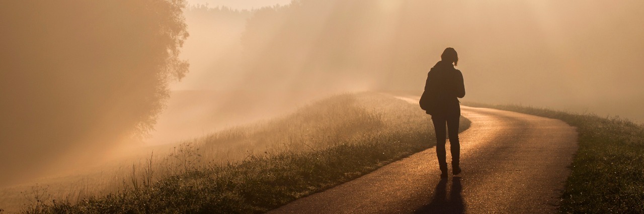 Woman walking on a road in the morning fog