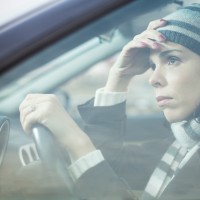 Mid adult looking away with sad expression while driving her car