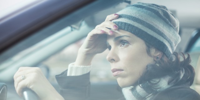 Mid adult looking away with sad expression while driving her car