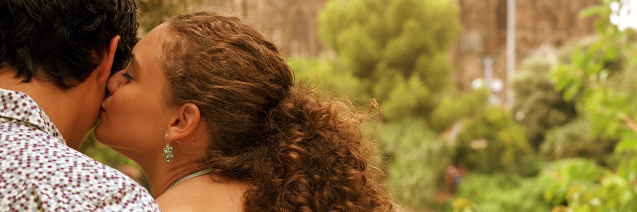 What to Do When You Have a Chronic Disease and Sex Is Hard couple sitting outdoors, woman kissing man, rear view