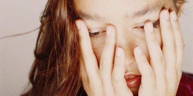 woman covering face with hands looking down