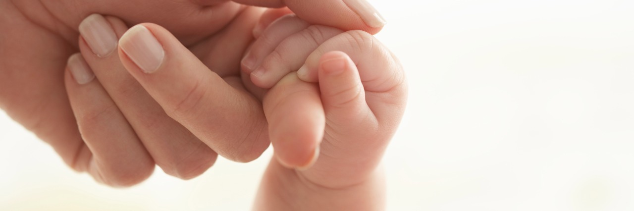 photo of baby girl holding woman's hand in sunlight