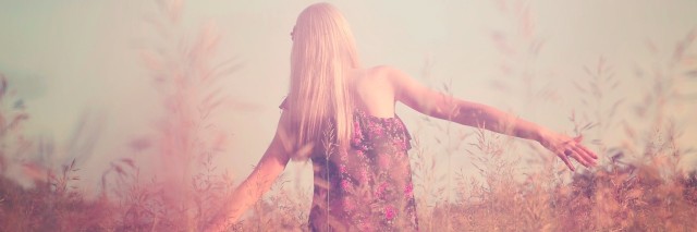 Retro toned portrait of young girl in summer field from back