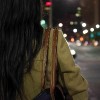 Woman standing at a street intersection at night with out of focus lights