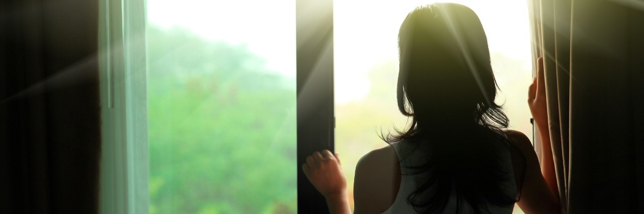 How I Decided to Accept My Illness and Keep Smiling girl opening curtains in a bedroom