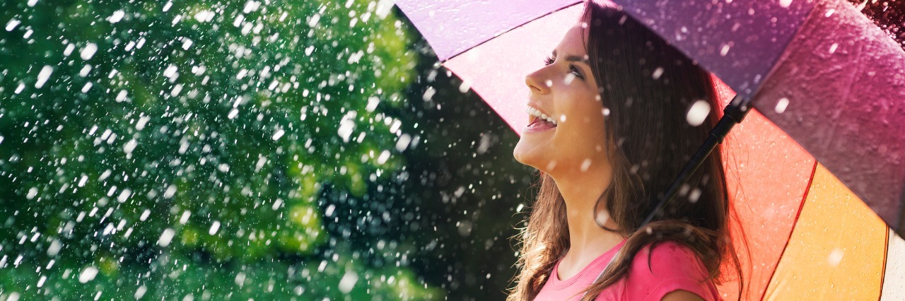 woman holds colorful umbrella in the rain and laughs