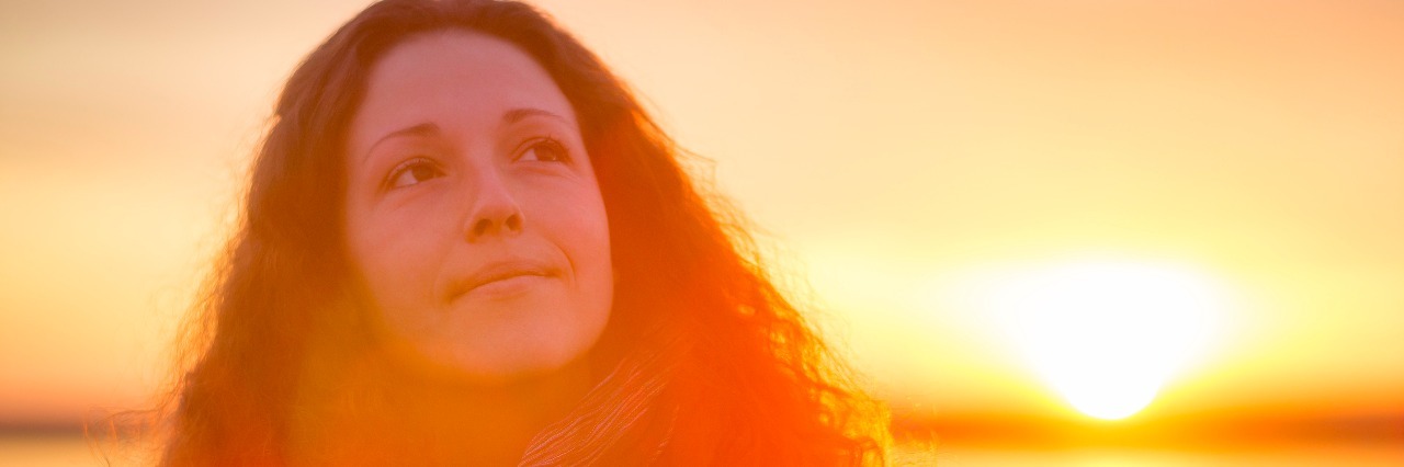 5 Reasons to Find Hope in Chronic Pain young woman enjoying the beautiful sunset at the sea.
