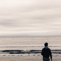 Picture of man from behind walking on a beach on an overcast day