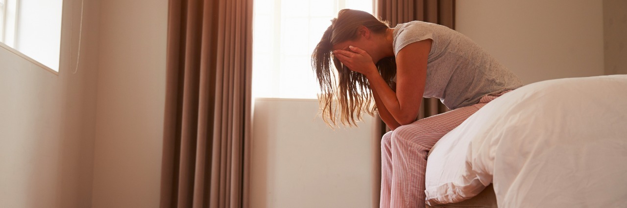 Things That Can Make Fibromyalgia Symptoms Worse Woman Suffering From Depression Sitting On Bed In Pajamas