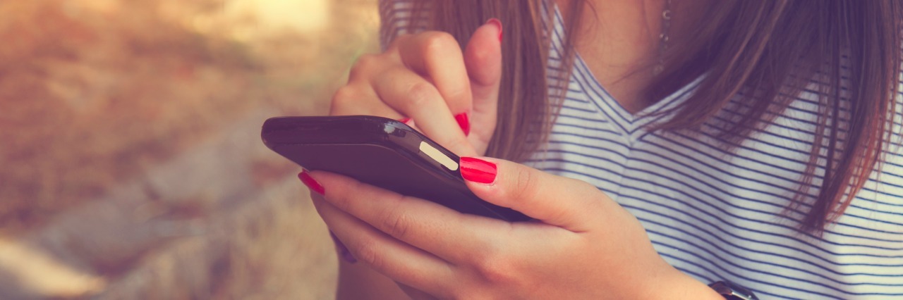 The Cell Phone Theory of Energy With Chronic Illness Young woman using cellphone outdoors.